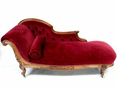 A Victorian walnut-framed chaise longue upholstered in red button-back velour, with carved scroll and on squat cabriole legs, length 185cm.