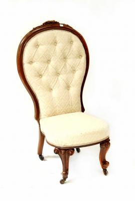 A Victorian walnut spoon back bedroom chair with carved decoration, on squat cabriole legs, upholstered in a button-back cream woven fabric.