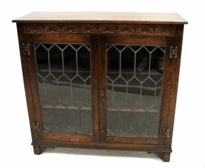 An early 20th century glazed bookcase with carved decoration to the frieze, above pair of astragal glazed doors, raised on stile supports, height 92cm, width 95cm, depth 33cm.