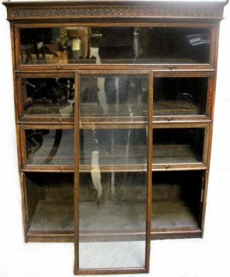 An early 20th century oak bookcase with four sections, each with glazed up-and-over door, carved detail to the frieze and lower section, raised on squat cabriole legs, height 161cm, width 115cm, depth 37cm (af).