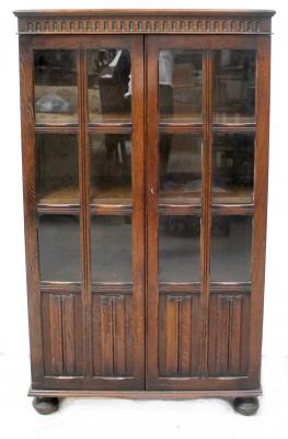 An early 20th century oak Priory-style display cabinet with pair of glazed doors with linen fold lower section, height 136cm, width 79cm, depth 35cm.