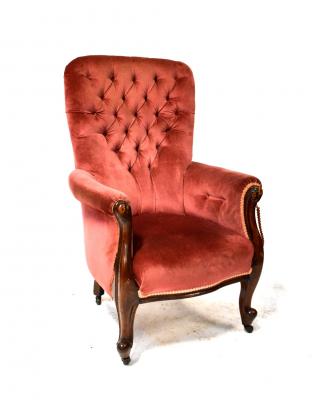 A Victorian mahogany button-back armchair upholstered in pink velour and with scroll ends, on cabriole legs with castors.