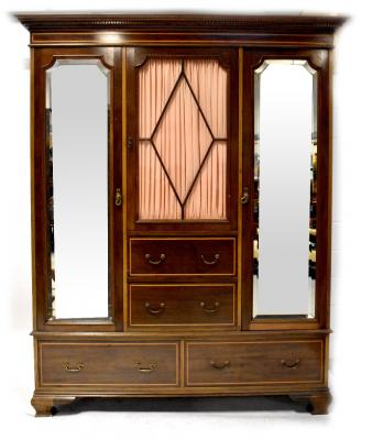An Edwardian inlaid mahogany triple compactum wardrobe, the central section with glazed door above two short drawers flanked by a pair of mirrored doors above a base of two long drawers, on ogee bracket feet, 215 x 175 x 59cm