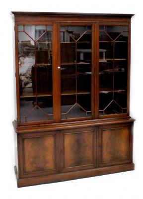 A reproduction mahogany bookcase, the top with three astragal glazed panels above a base with three panelled cupboard doors, on a plinth base, height 210cm, width 157cm, depth 41cm.