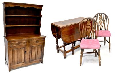 A mid-20th century oak dining suite comprising a drop-leaf dining table to wrythen supports and cross stretcher, raised on ball feet, width when extended 122cm, four matching wheel back chairs and a Colonial-style stained oak dresser, curved top rail above two plate racks to two drawers above two panelled doors, on block supports, 177 x 115 x 45cm (6).