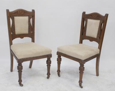 A set of four Victorian carved walnut salon chairs upholstered in studded cream suedette, on turned legs with castors (4).