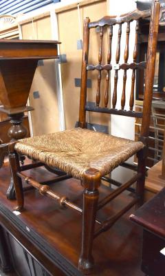 An 18th century rush seated nursing chair, the back rest with two rows of spindles, on turned tapering legs united by stretchers, to pad feet.