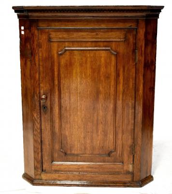A George III oak wall hanging corner cupboard, three interior shaped shelves, door with raised bead relief, to a stepped plinth base, height 99cm, width 78cm.