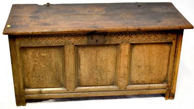 An 18th century and later oak coffer, three-panel front with iron lock, carved Celtic-style top rail, period blacksmith handles, two-plank top, on square stile supports.