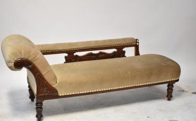 An Edwardian mahogany chaise longue with scroll back and open arm, upholstered in a mushroom-coloured velveteen fabric, the back with pierced carving, to turned legs, length approx 190cm.
