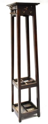 An Arts and Crafts oak hall stand, the top of square form above six hooks, on square tapering legs with an open rack to the centre for umbrellas with drip tray beneath, height 189cm.