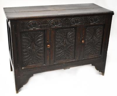 An 18th century oak mule chest with plank top above carved front, the frieze with flower and foliate motifs, above a pair of cupboard doors flanking a central fielded panel, raised on bracket feet, 92 x 126 x 55.5cm.