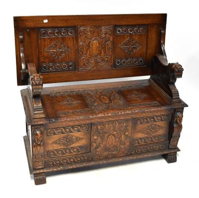 A late 19th/early 20th century oak monks' bench with three panels to the back and carved top rail, the seat with foliate and scroll carving, to block supports, 95 x 105 x 42cm.