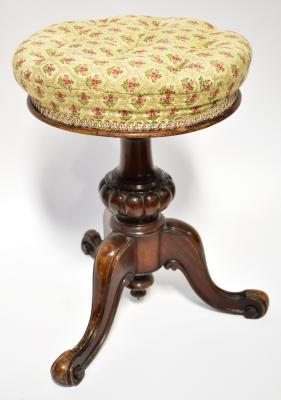 A Victorian mahogany adjustable height piano stool, with button upholstered circular seat in cream woven material with heather motif within diamond shaped borders, on turned and bulbous column to tripod cabriole legs, diameter 35cm.