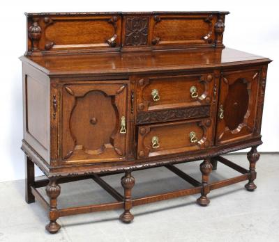 An early 20th century medium oak stained sideboard with galleried back and central bank of two drawers flanked by panel door cupboards, supported on carved turned legs united by a peripheral stretcher, approx width 152cm.