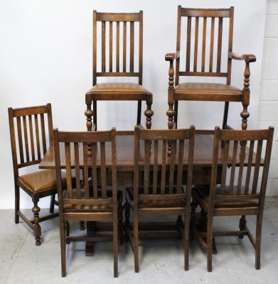An early 20th century oak extending Jacobean refectory-style draw-leaf dining table on turned baluster supports and cross-stretcher, length when extended 153cm, a set of five similar refectory Jacobean-style oak dining chairs and one matching carver (7).
