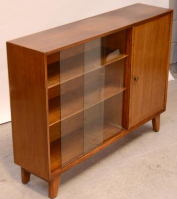A contemporary walnut and oak bookcase, two interior shelves, two sliding glass doors, cupboard door to one side, on tapering block supports, 80 x 106cm.