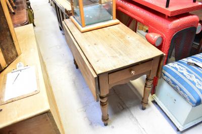 A 19th century rustic pine kitchen table with short plank drop flaps and side cutlery drawer, 77 x 115 x 61cm (unextended), 77 x 115 x 110cm when extended.