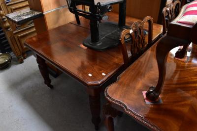 An early 20th century mahogany wind-out extending dining table, with canted corners and raised on reeded supports to brass caps and castors, 74 x 125 x 106cm (af).