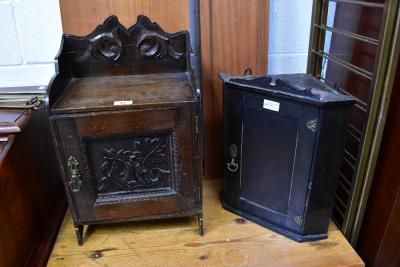Two antique wall-mounted cabinets to include a smokers' cabinet with oak leaf carved panel to the front, height 54cm, and a small corner cabinet with swan neck top and external brass hinges, height 42cm (2).