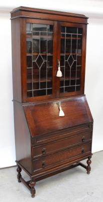 A 1920s stained oak bureau bookcase, the twin doors with leaded lights, three fixed shelves to interior, above a fall-front on mechanical lopers with fitted interior, over two-drawer base supported on turned legs united by an H-stretcher, height 199.5cm.