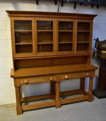 A modern bespoke made large and impressive kitchen dresser with two glazed display cabinets revealing two plate rack shelves and lower recess, on substantial dresser base, with two long drawers and turned circular handles, raised on three ring turned front supports, on square bases united by plank stretchers, in two sections, height of both sections combined 214cm, width 198cm, depth 53cm.