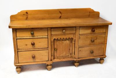 A late 19th/early 20th century large rustic kitchen dresser base, possibly sycamore and pine, the substantial, possibly one-piece top with back rail over central drawer over cupboard, with spindle columns flanked by two banks of three drawers, wooden turned handles, on baluster turned supports, 104 x 178 x 55cm.