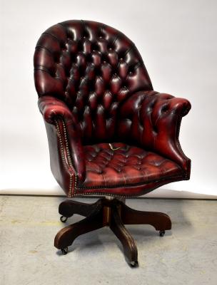 A reproduction oxblood leather button pressed office revolving armchair, raised on five reeded outswept supports to castors (af).