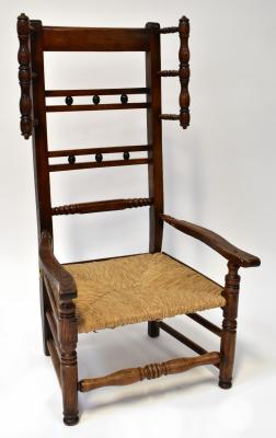 A late 18th/early 19th century rush seated low chair with high back, bobbin turned handles to each top side, two rails divided by three wooden balls, turned stretcher, shaped arms, rush seat, united with turned front stretcher and double side stretchers, possibly reduced in height, possibly formerly a rocking chair, height to top of seat 29cm.