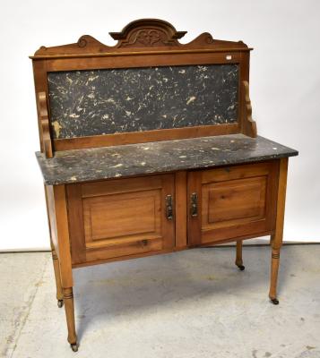 An Edwardian walnut marble-top wash stand, the raised back with carved pediment above pair of fielded panelled doors, raised on ring turned supports to castors, 133 x 106 x 46cm.