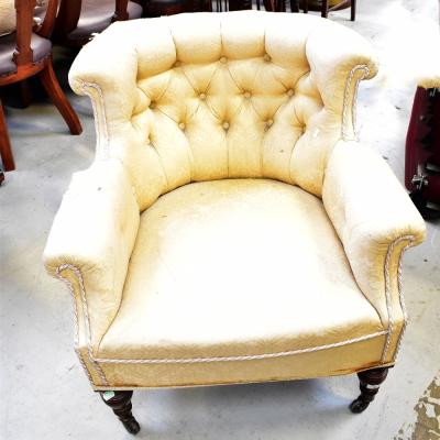 A Victorian walnut framed low button pressed tub chair, with scrolling arms and turned front legs, to brass caps and castors.