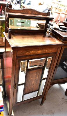 A 19th century rosewood mirrored side cabinet, the raised back set with a small shelf and small rectangular bevelled mirror, above single door centred with an inlaid panel with swag and urn decoration, surrounded by six small rectangular bevelled mirrors above shaped apron and raised on square tapering supports to castors, approx 133 x 56 x 37cm.