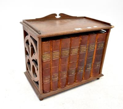 A late 19th century Gothic oak small bookstand with pierced detail to the sides, containing seven volumes of La Rousse Nouveau Illustré, height 44, width 51cm.
