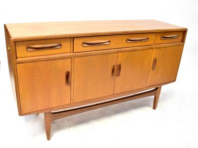 G PLAN; a mid-20th century teak sideboard with three drawers over four doors, on shaped stretcher base, 84 x 152 x 48cm.