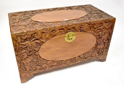 A camphor wood carved blanket box profusely decorated with flowers and fruit, on bracket feet, 59 x 104 x 52cm.