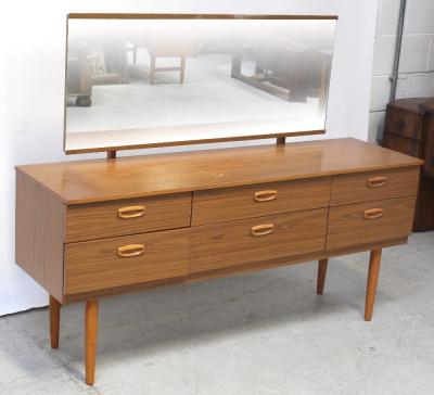 A retro teak-effect rectangular mirror-back dressing table with two central long drawers and two short drawers to either side, on tapering turned supports, length 152cm.
