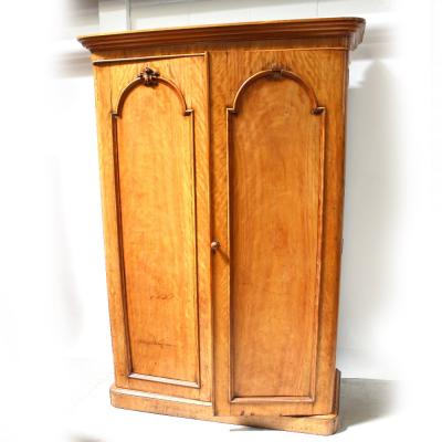 A Victorian satin walnut two-door rounded-corner wardrobe with arched panel doors and flared cornice, height 206cm.