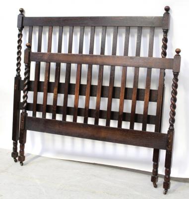An early/mid 20th century oak bedhead and foot with slat back and wrythen supports to either end.