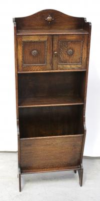 A c1930s oak slender bookcase, two small cupboard doors over one shelf and lower magazine rack, to block supports, 124 x 45cm.