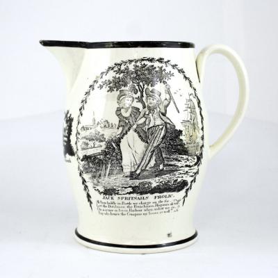 A c1780 Liverpool creamware jug decorated with comical scene to one side entitled 'Jack Spirit Sales Frolic' with small rhyme beneath, below the spout a vignette of a small boy and cockerel with the legend 'Time to Rise, Be Attentive to Business' and on the opposing side a bat print of a three-masted ship with a banner beneath amongst cannon reading 'Success to Trade', height 22cm.