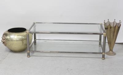 A tubular chrome glass coffee table, length 122cm, an umbrella-shaped umbrella stand and a large brass planter with bronze lion mask bosses to either side.