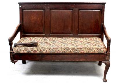 A George III oak bench settle, three panels to curved arm rests to front cabriole supports and pad feet, 150cm (af).