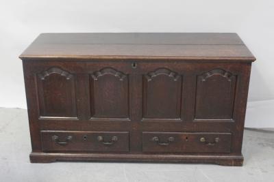 An 18th century oak panel mule chest, plank top on strap hinges, enclosing candle box and match drawers, over a two-drawer base on shaped plinth, width 140cm.