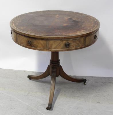 A 19th century mahogany rent table, the red tooled leather top surmounting four blind and four frieze drawers, on a tripartite pedestal base, to hairy paw slipper castors, diameter 82cm.