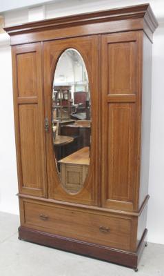An Edward VII mahogany single-door wardrobe, the door with oval bevelled mirror and on single-drawer base, height approx 205cm.