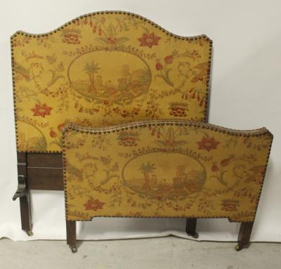 A late 19th century single bed frame in the French style, fabric-covered headboard and footboard with figural and floral decoration.