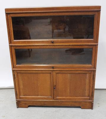 A Globe Wernicke style oak two-tier bookcase, with up-and-over glazed doors above two panelled cupboard doors.