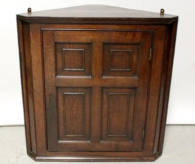 An oak wall-hanging corner cupboard, the single panelled door enclosing two shelves, approx 93 x 91cm.