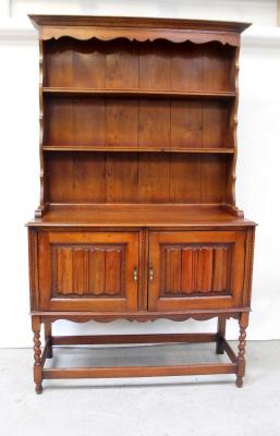 A reproduction stained oak dresser, the top with plate racks on a base with linenfold carved cupboard doors, on barleytwist legs, height 208cm, width 122cm.